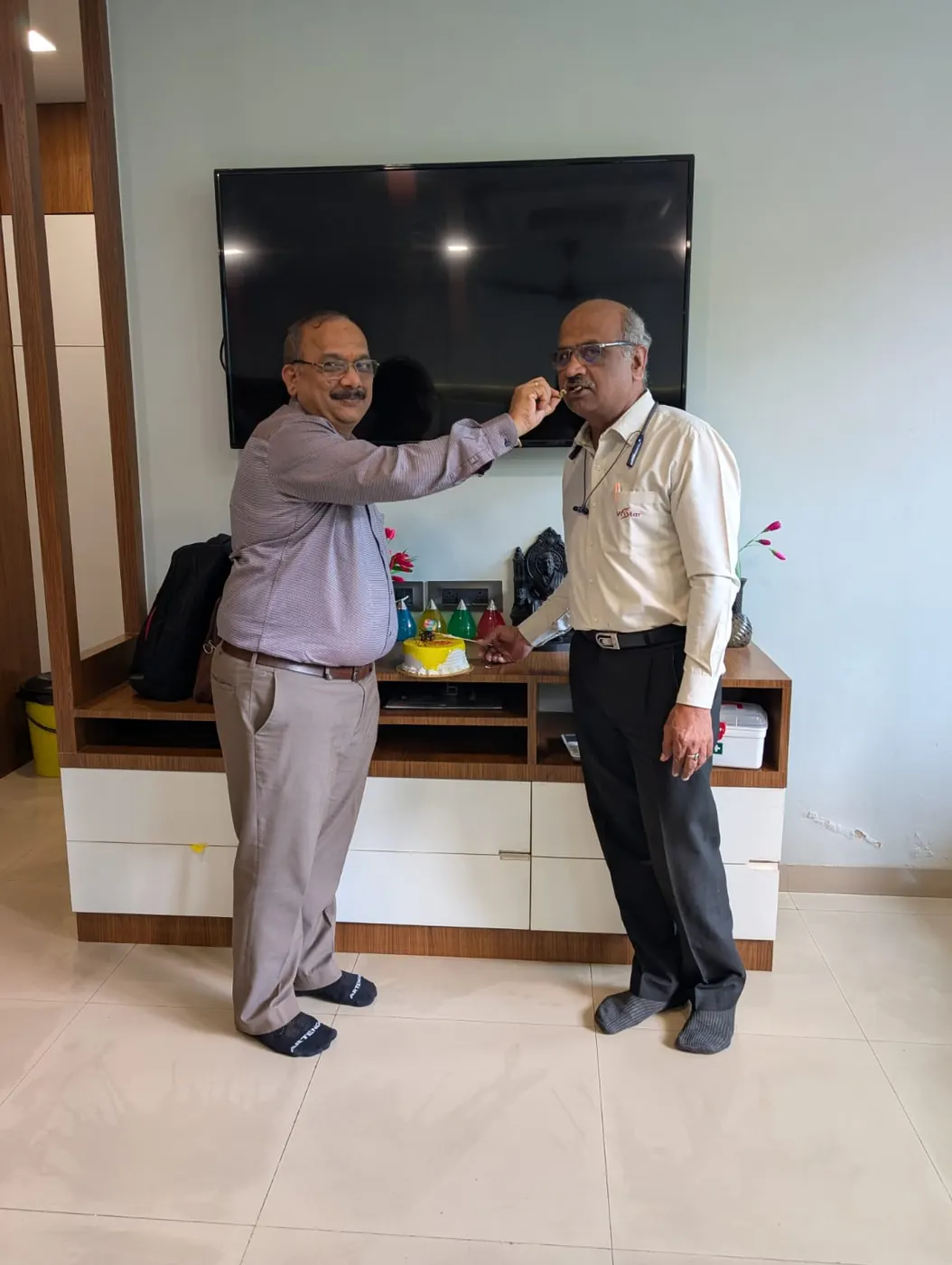 A second frame of colleagues sharing cake at the office celebration
